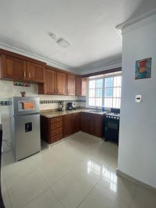a kitchen with wooden cabinets and a stainless steel refrigerator at CEDOTURT Hotel Boutique & Escuela in Santo Domingo