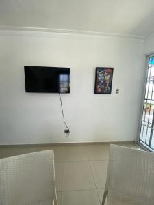 a room with two chairs and a flat screen tv on a wall at CEDOTURT Hotel Boutique & Escuela in Santo Domingo