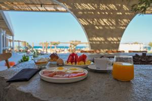a table with a plate of food and a glass of orange juice at Glaronissi Beach in Plaka