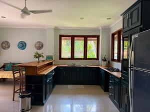 a kitchen with dark green cabinets and a counter top at 3 Bedroom Private House - Tir Na Nog in Gili Trawangan