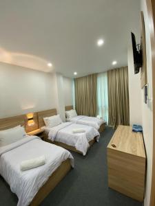 ein Hotelzimmer mit drei Betten und einem Fernseher in der Unterkunft Cristam in Biskra