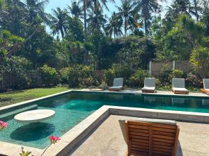 a swimming pool with two chairs and a table at 3 Bedroom Private House - Tir Na Nog in Gili Trawangan
