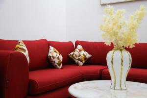 ein rotes Sofa mit einer Blumenvase auf einem Tisch in der Unterkunft Cristam in Biskra