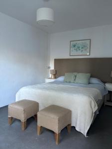 a bedroom with a large bed with two stools at Posada Las Chacras in Ciudad Lujan de Cuyo