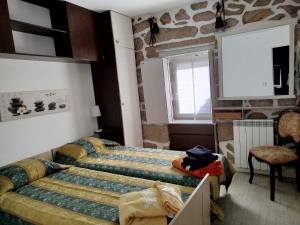 a bedroom with a bed and a chair and a window at Casinha de Lamares in Vila Real