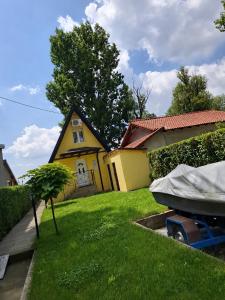 a small yellow house with a small tree in the yard at Vila Andreoni,na obali Dunava in Kovin