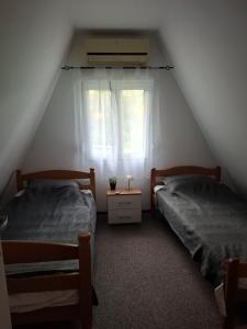 two beds in a attic bedroom with a window at Vila Andreoni,na obali Dunava in Kovin +4 photos