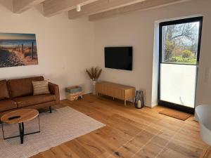 a living room with a couch and a flat screen tv at Gulfhof Wangermeer 2 Tilda in Hohenkirchen