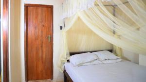 a bedroom with a bed with a canopy and a wooden door at Kethbima Agri Cottage in Amunugama