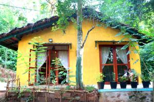 a yellow house with a person sitting in a window at Kethbima Agri Cottage in Amunugama
