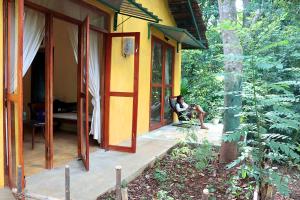 a person sitting on the porch of a house at Kethbima Agri Cottage in Amunugama