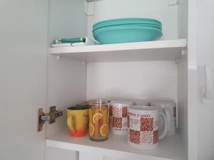 a shelf with cups and bowls in a kitchen at Apartmani Zoka in Niš