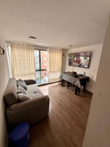 a living room with a couch and a table with a television at Fly At Home Bogotá in Bogotá