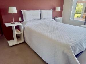 a bedroom with a large white bed with two night stands at El Prado Chico, Casa de Campo in Salta