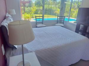a bedroom with a bed with a lamp and a window at El Prado Chico, Casa de Campo in Salta
