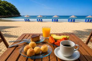 a table with food and a cup of coffee on the beach at Hotel Canto do Rio Maresias in Maresias