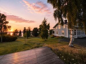 a house with a wooden deck in front of a sunset at Villa Fridhem, Härnösand in Härnösand +20 photos
