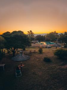 a person sitting in a chair under an umbrella at sunset at Apart hotel Agua Dorada in Cavalango