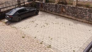 a black car parked on a brick sidewalk at Lux Stays in Prishtinë