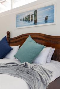 a bed with white and blue pillows on it at Kai Cottage in Bergvliet +13 photos