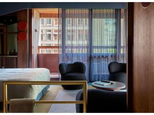 a hotel room with a bed and two chairs and a table at Hyde Melbourne Place in Melbourne