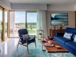 a living room with a blue couch and a table at Victoria Golf Resort and Spa Managed by Accor in Vilamoura