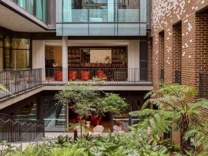 a building with a courtyard with trees and chairs at 25hours Hotel Sydney The Olympia in Sydney
