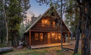 a log cabin in the woods with a deck at The Hailey Cabin in Island Park