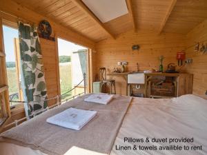 a bedroom with a bed in a wooden room at The Hoppers Hut in Weald