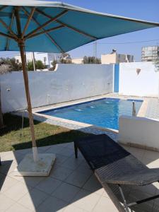 a swimming pool with an umbrella and a table and chairs at Ridha in Djerba