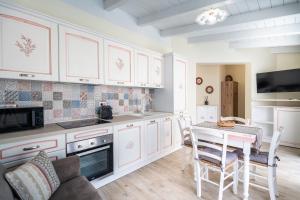 a kitchen with white cabinets and a table with chairs at Su Mari in Villasimius