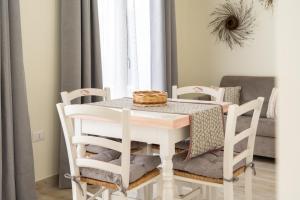 a white dining room table and chairs with a wicker basket on top at Su Mari in Villasimius +25 photos