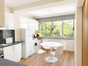 a kitchen with white cabinets and a white table and chairs at Lovely & Comfy 3 in Estoril