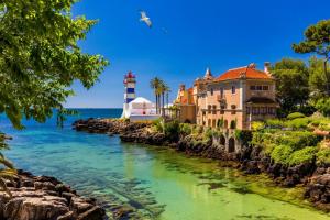 a lighthouse and a building next to a body of water at Lovely & Comfy 3 in Estoril