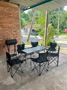 a picnic table with chairs and a grill on a patio at Rumah Singgah in Bentong
