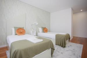two beds in a room with white walls at Porto & Douro Vista Apartments by Inviting in Valbom