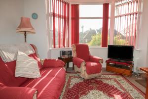 a living room with a red couch and a tv at Sylvian in Bexhill