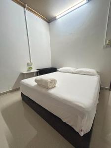 a bedroom with a bed with white sheets and pillows at Rumah Singgah in Bentong