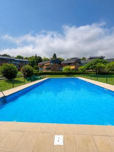 a large blue swimming pool in front of some buildings at Hondarribia con Piscinas, Terraza Privada, Parking y Tenis - CASA OLABIDE in Hondarribia