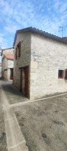 a white brick building with two doors on a street at Gîte de l'Aiguillier in Castelnau-de-Montratier