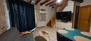a living room with a table and a flat screen tv at Gîte de l'Aiguillier in Castelnau-de-Montratier