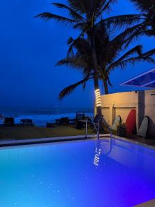 a swimming pool with a palm tree next to the ocean at Ayomal Beach Paradise in Galle