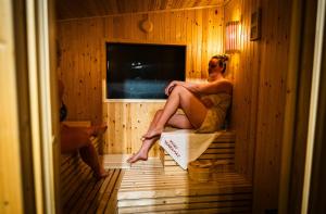a woman is sitting in a sauna at Nyiko Vendégház in Lupeni