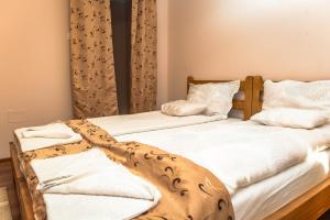 two beds with white sheets and a blanket at Nyiko Vendégház in Lupeni