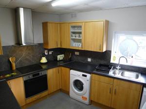 a kitchen with wooden cabinets and a washing machine at Saltoun House in Fraserburgh