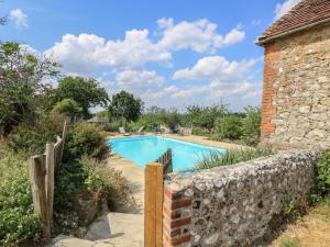 a pool with a stone wall next to a house at Byre Cottage 2 in Pulborough