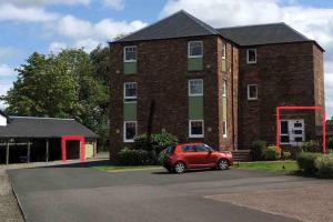 a red car parked in front of a brick building at The Little Beech Tree in Linlithgow