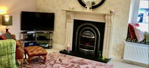 a living room with a fireplace and a tv at The Little Beech Tree in Linlithgow +39 photos