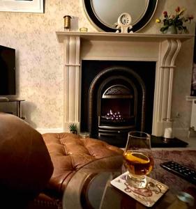 a living room with a fireplace and a glass of wine at The Little Beech Tree in Linlithgow