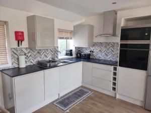 a kitchen with white cabinets and a black counter top at Exeter Executive Apartments in Pinhoe